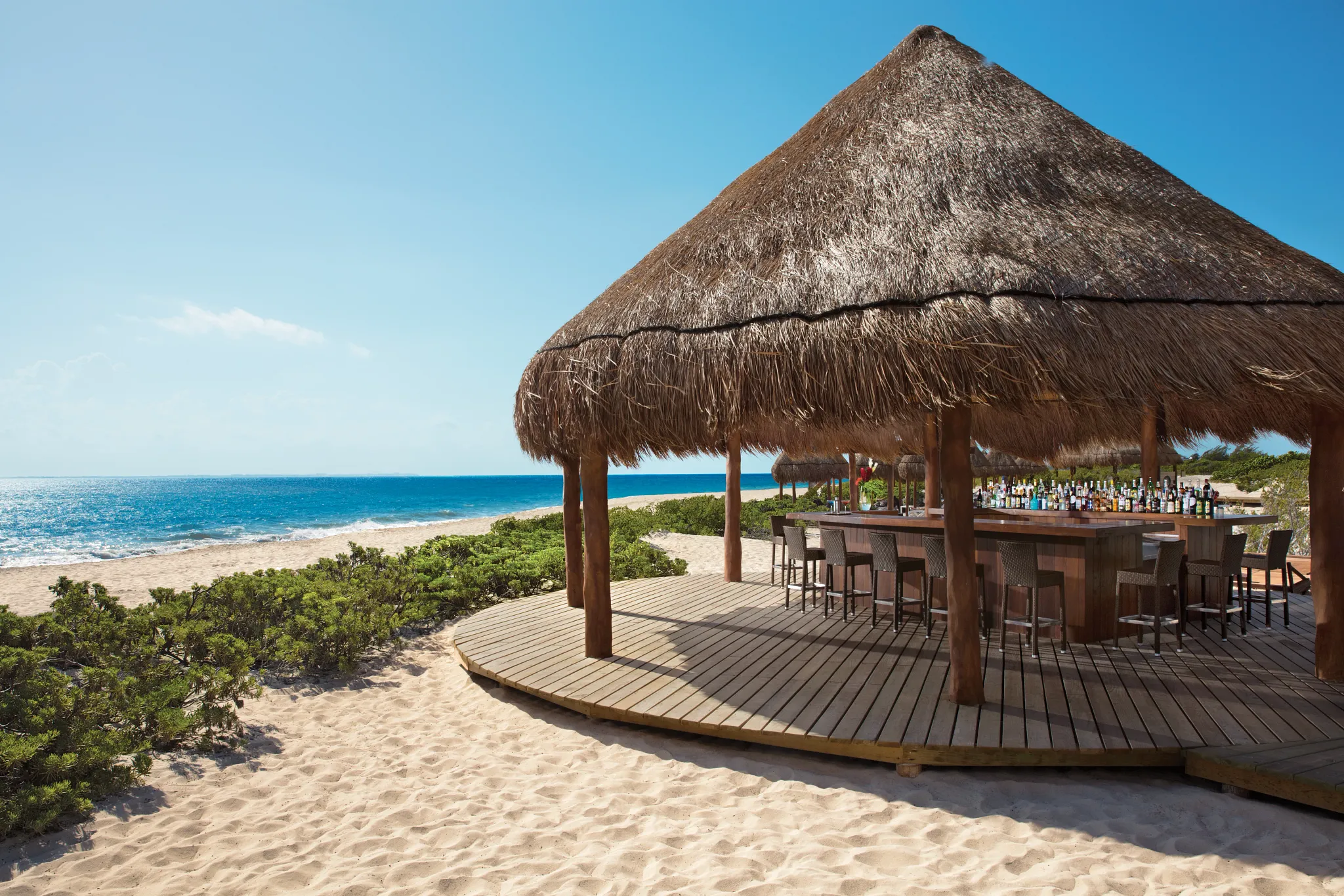 Hideaway beach bar at Dreams Playa Mujeres Golf & Spa Resort featuring a relaxed oceanfront setting with tropical cocktails and shaded lounge seating.