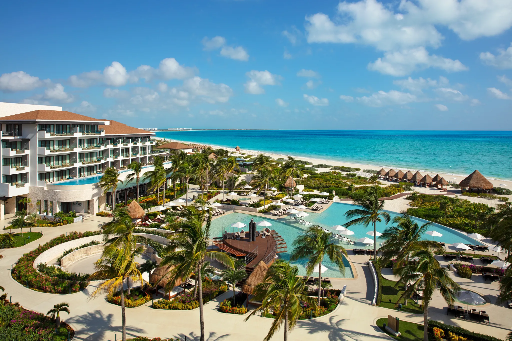 Main pool overlooking the Caribbean Sea at Dreams Playa Mujeres Resort with palm trees and beach access.