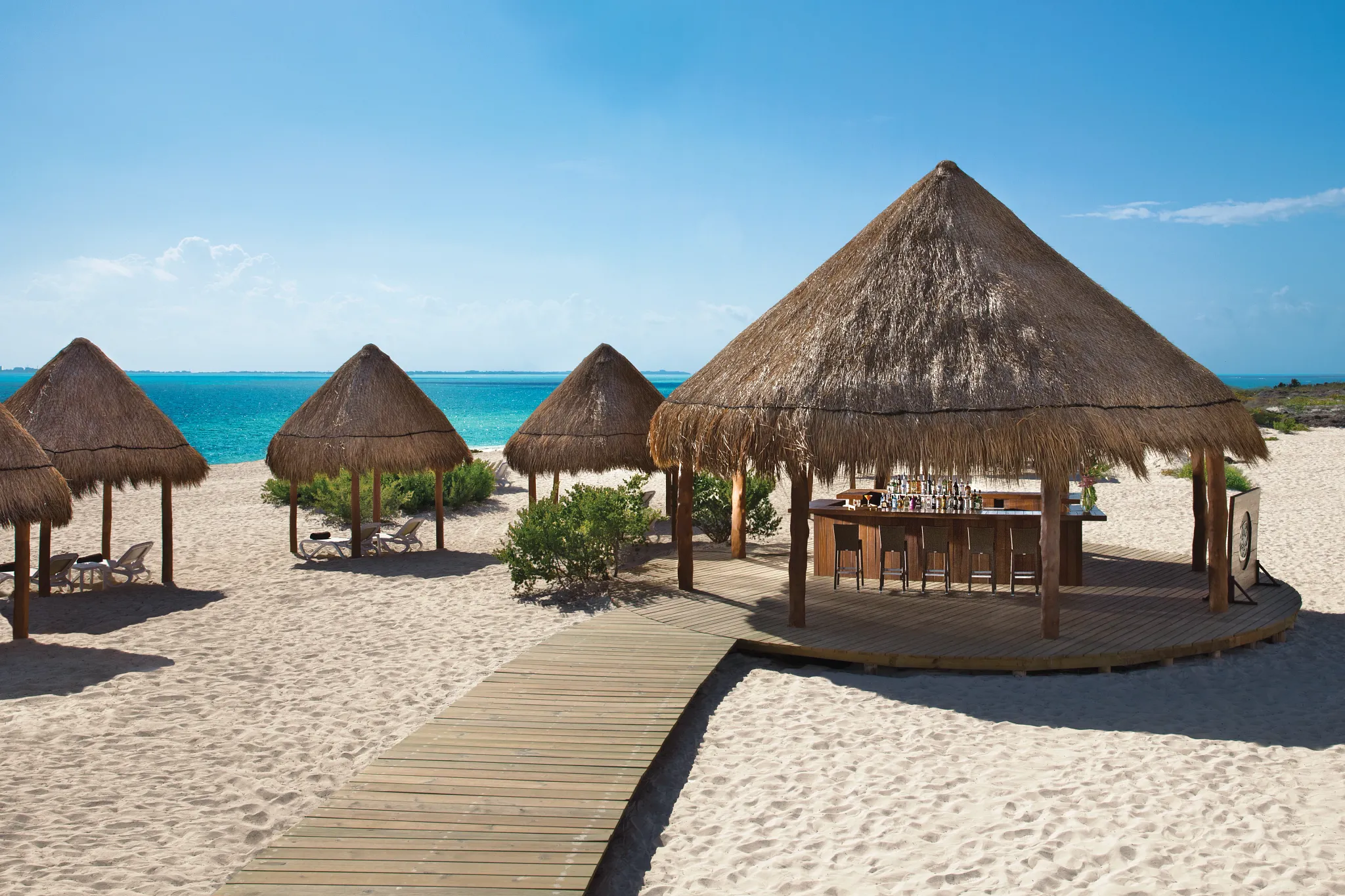 The Sand Bar at Dreams Playa Mujeres Golf & Spa Resort featuring a beachfront setting with tropical cocktails, shaded seating, and ocean views.